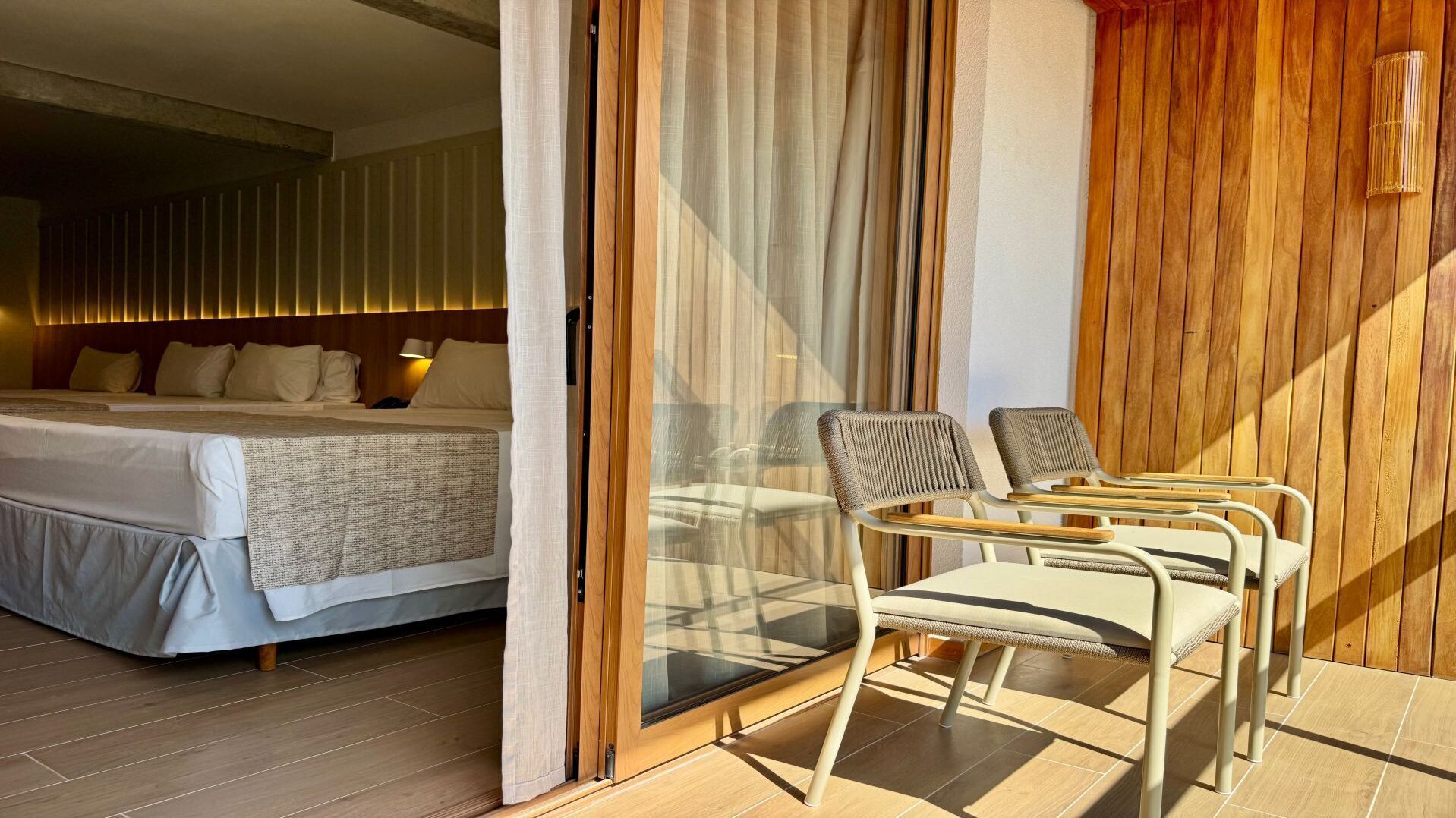 Une chambre d’hôtel avec un lit, un coin salon avec des fauteuils et une vue par la fenêtre.