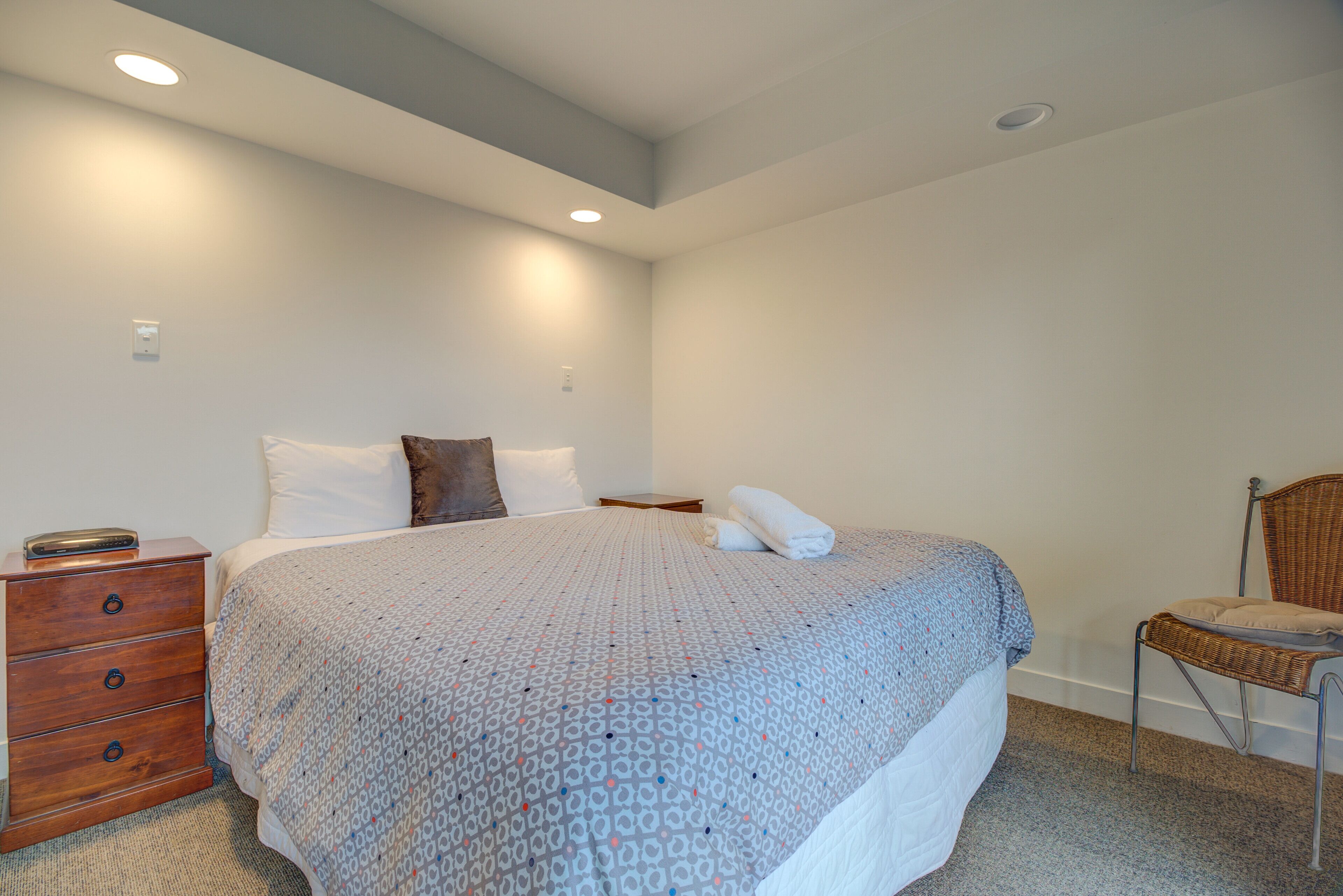A bedroom with a large bed, a wooden nightstand, a chair, and a small table.