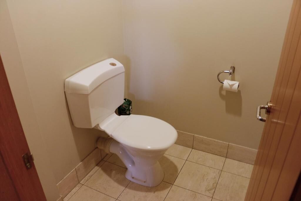 A small, clean bathroom with a white toilet, a toilet paper holder, and a door.