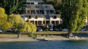 A multi-story hotel with a modern design, located near a body of water. - Lakefront Apartments (Queenstown)