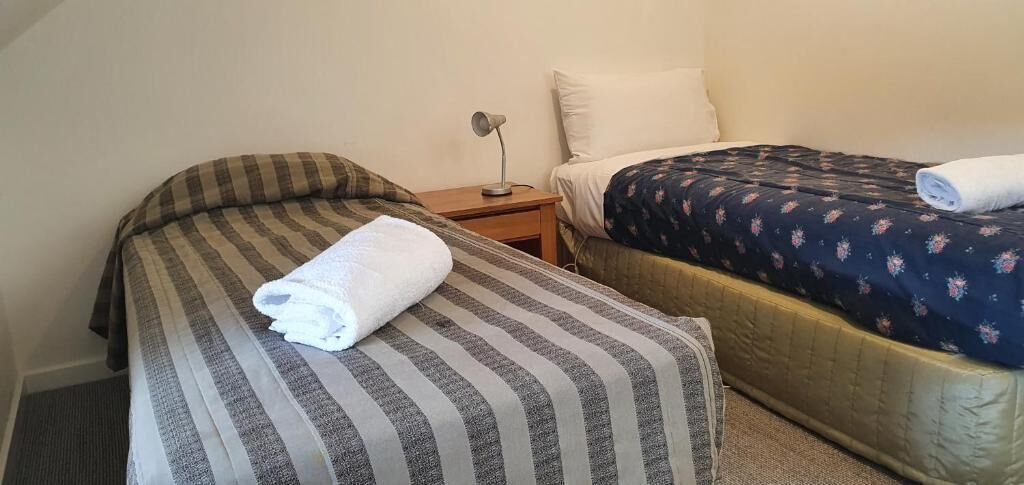 Un dormitorio con dos camas, una mesita de noche y una lámpara.