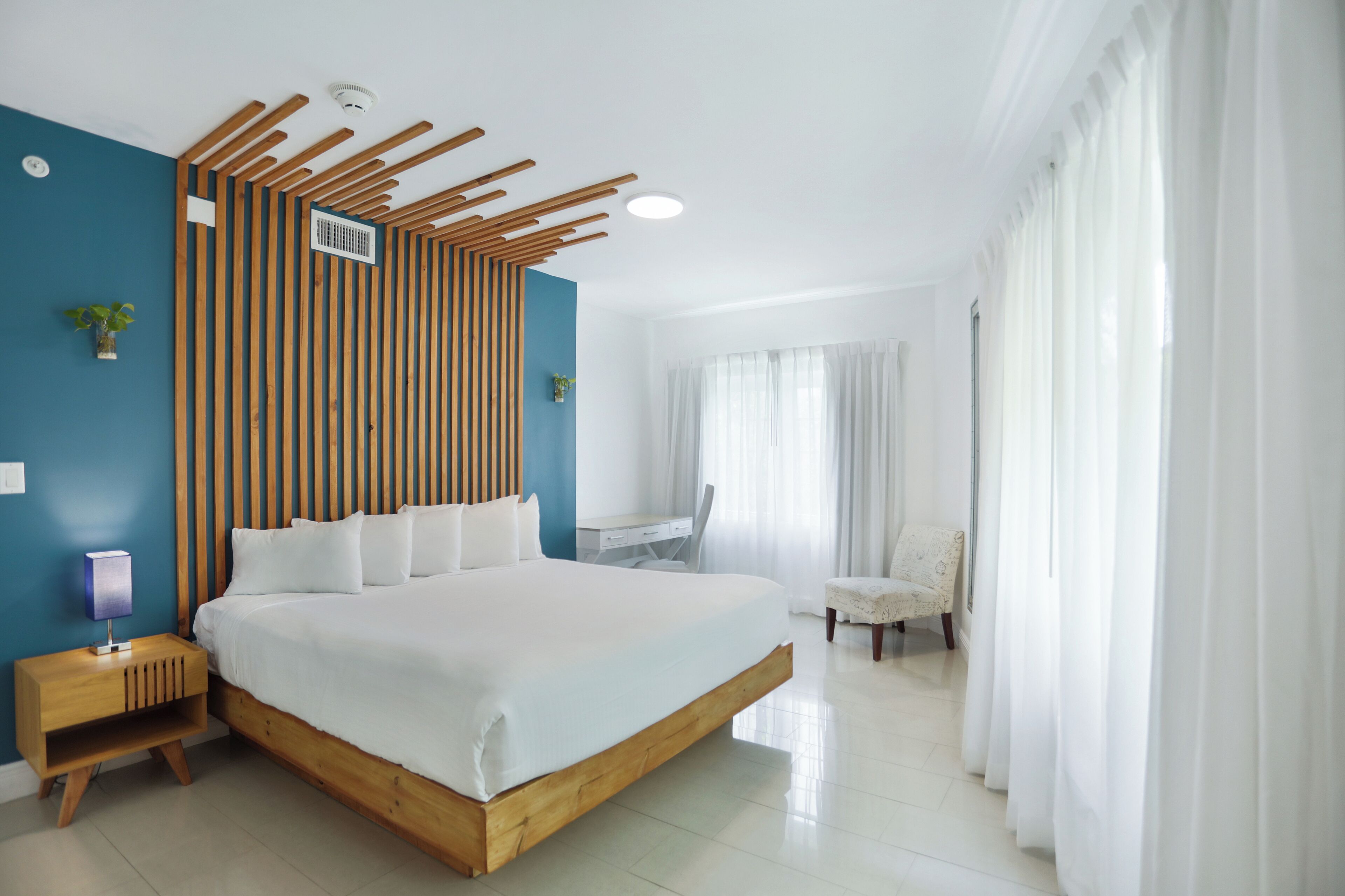 Ein modernes Schlafzimmer mit einem großen Bett, einem Holzschabrnenkopf, einem Schreibtisch und einem Stuhl.