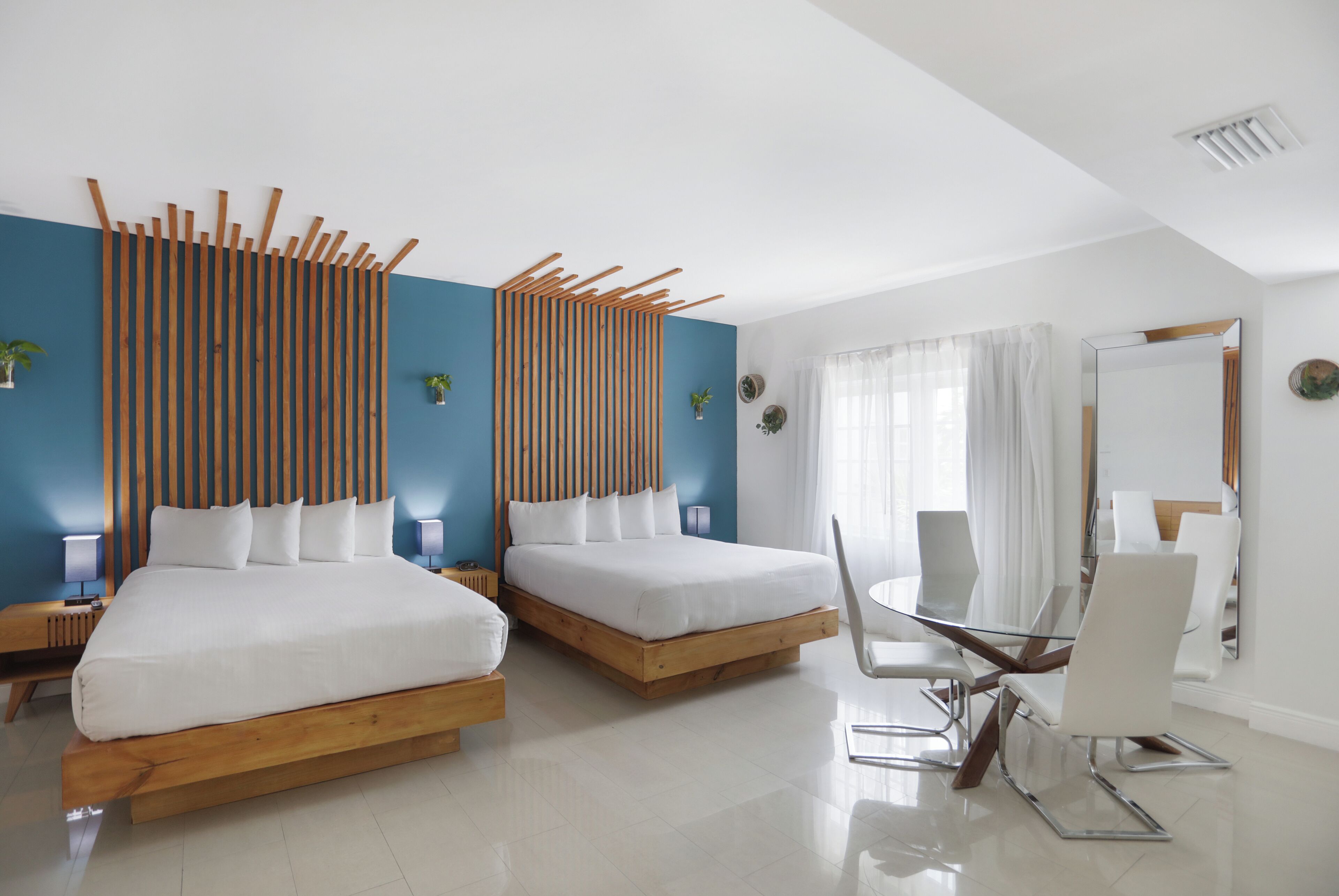 Ein modernes Hotelzimmer mit zwei Betten, einem Glastisch und einem großen Spiegel.