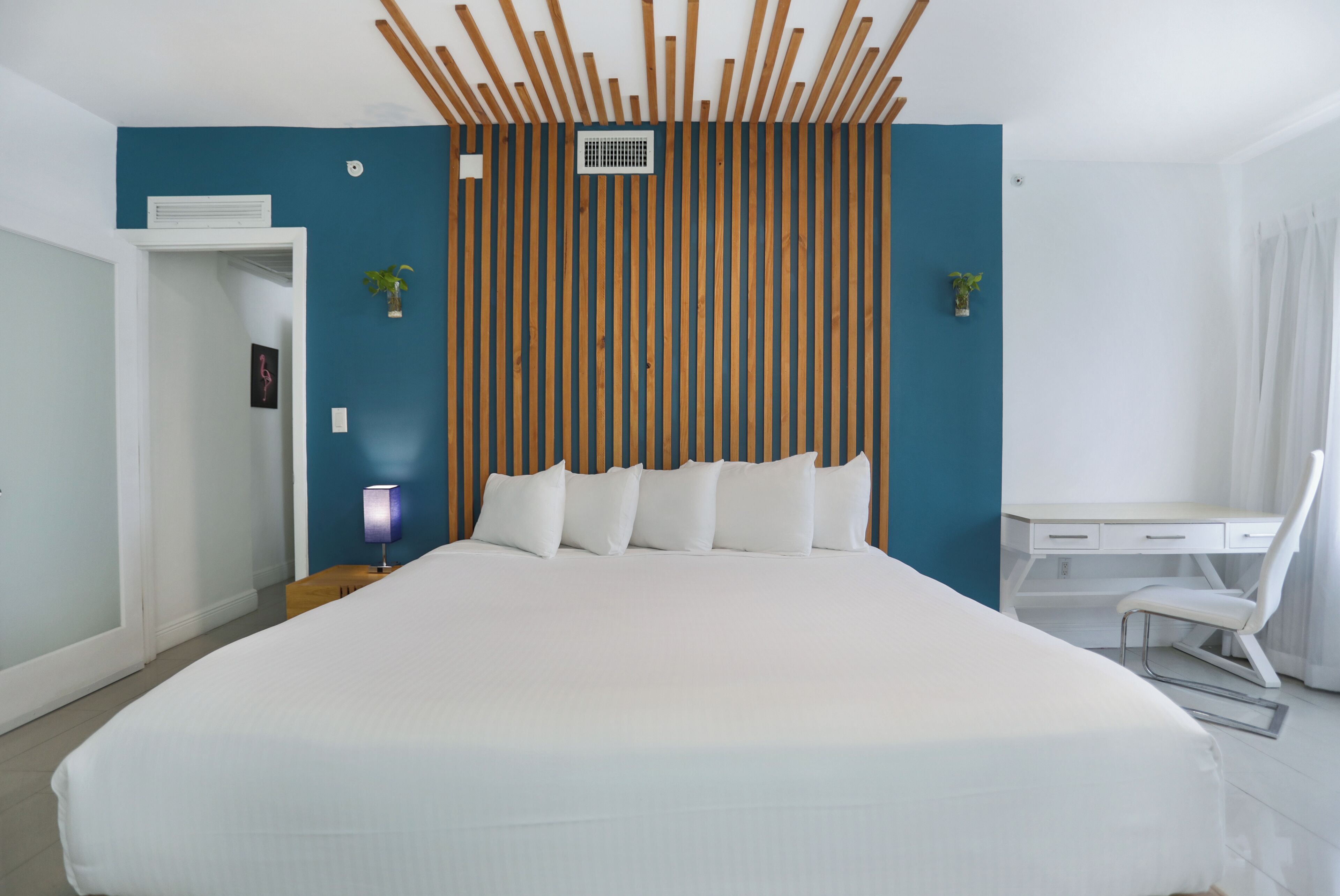 A modern hotel room with a large bed, a desk, and a chair.