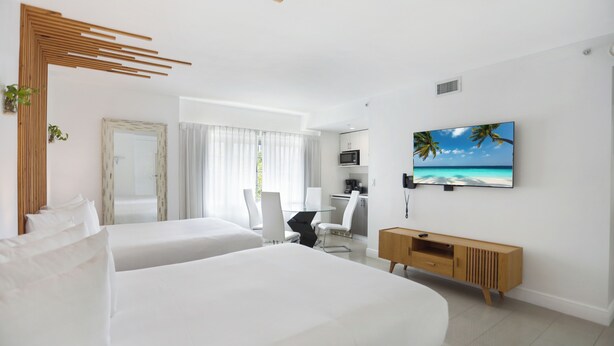 Une chambre d’hôtel moderne avec deux lits, un bureau, une télévision et une vue sur l’océan.