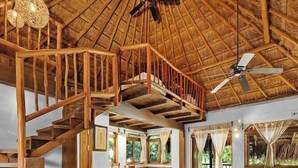 Una habitación amplia con escaleras de madera, una cama grande y un ventilador de techo.