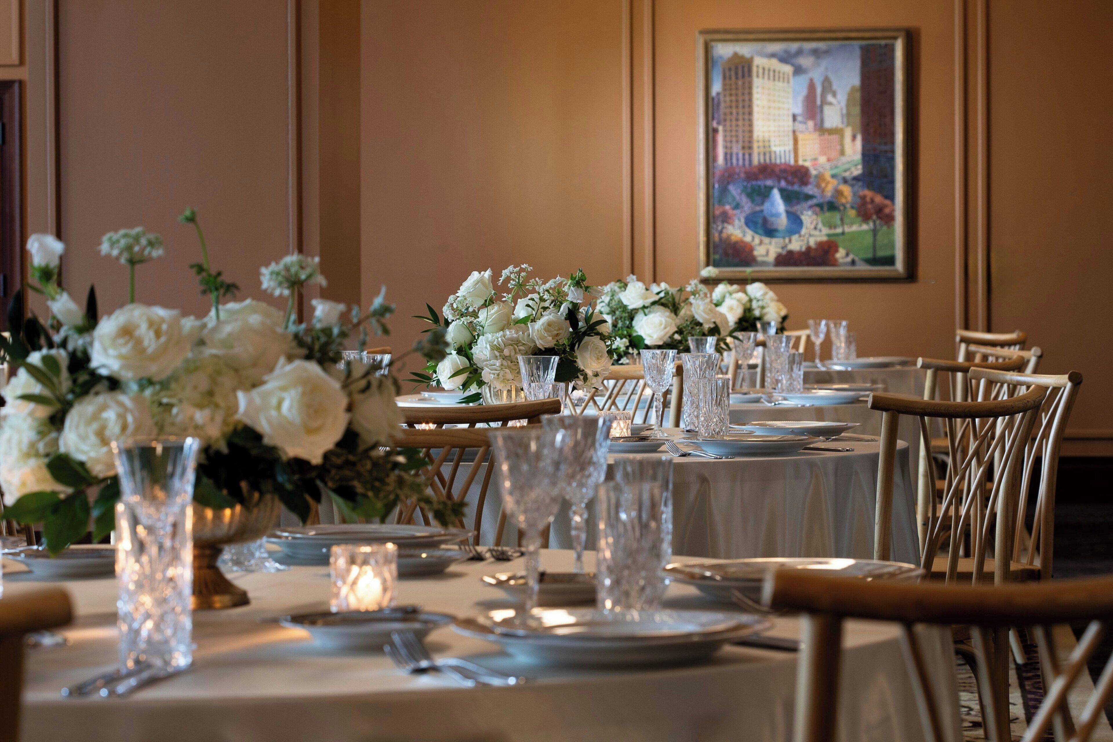 A dining area with tables set for a meal, featuring white floral centerpieces and clear glassware.