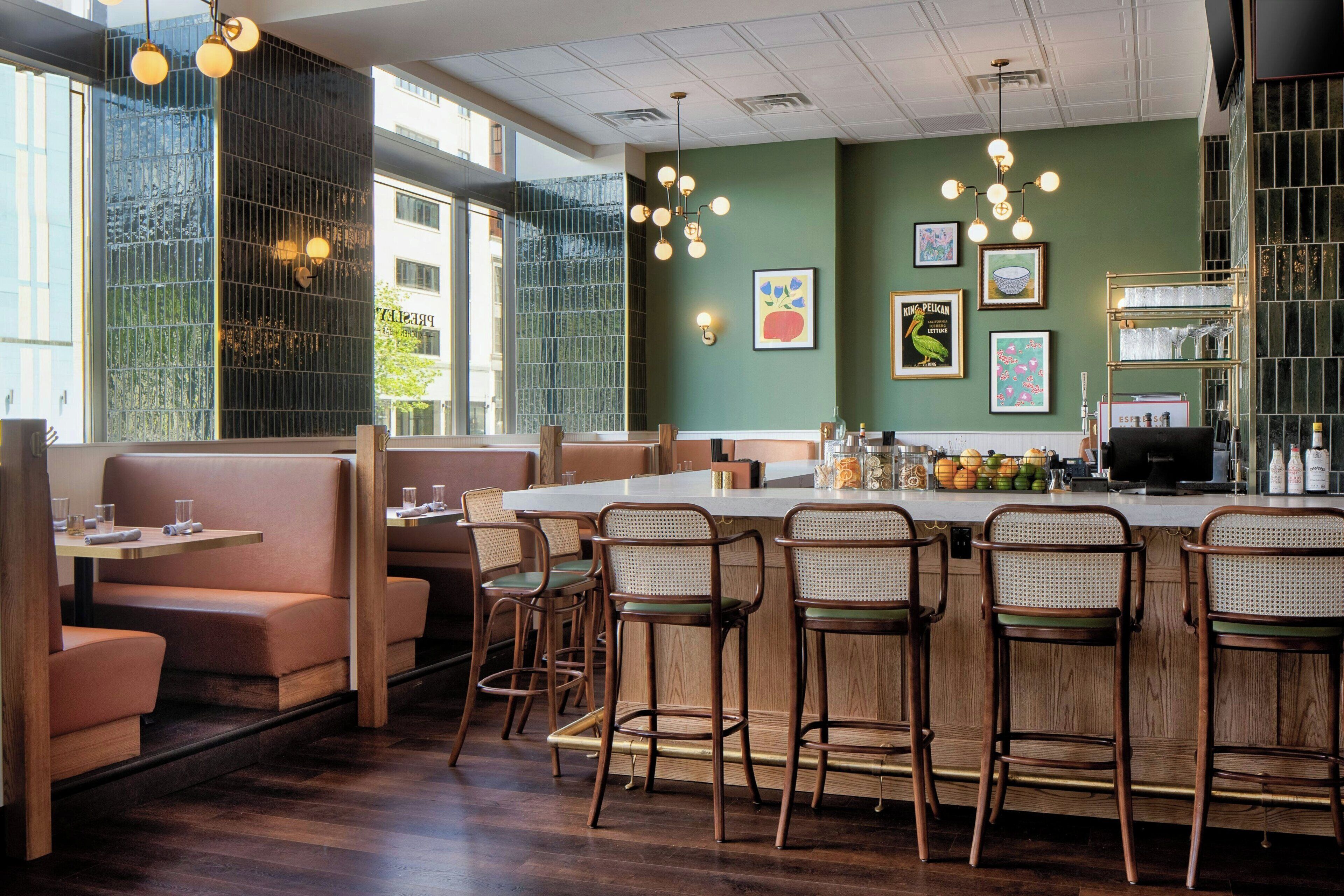 L’intérieur d’un restaurant avec des banquettes, des tabourets de bar et un espace bar.