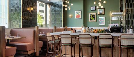 L’intérieur d’un restaurant avec des banquettes, des tabourets de bar et un espace bar.
