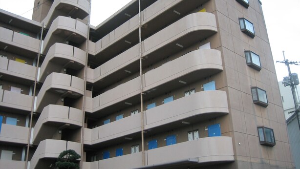 A multi-story building with a curved facade, balconies on each floor, and a mix of window types. - Sunwell Kotohira (Kotohira)