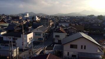 A residential area with various buildings, including houses and apartment complexes, with a mountain range in the background.