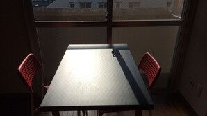 A small room with a wooden floor, a table, and two red chairs. - Sunwell Kotohira (Kotohira)