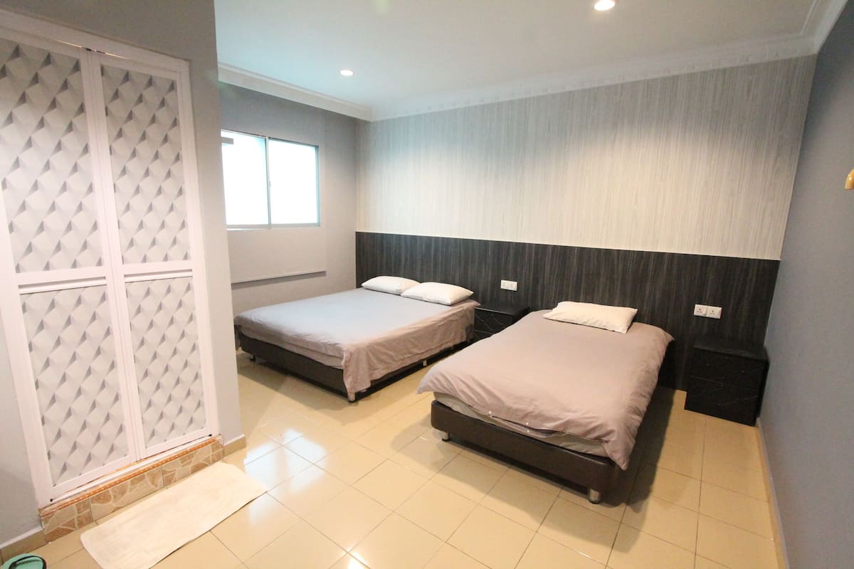 A bedroom with two beds, a window, a wardrobe, and a tiled floor.