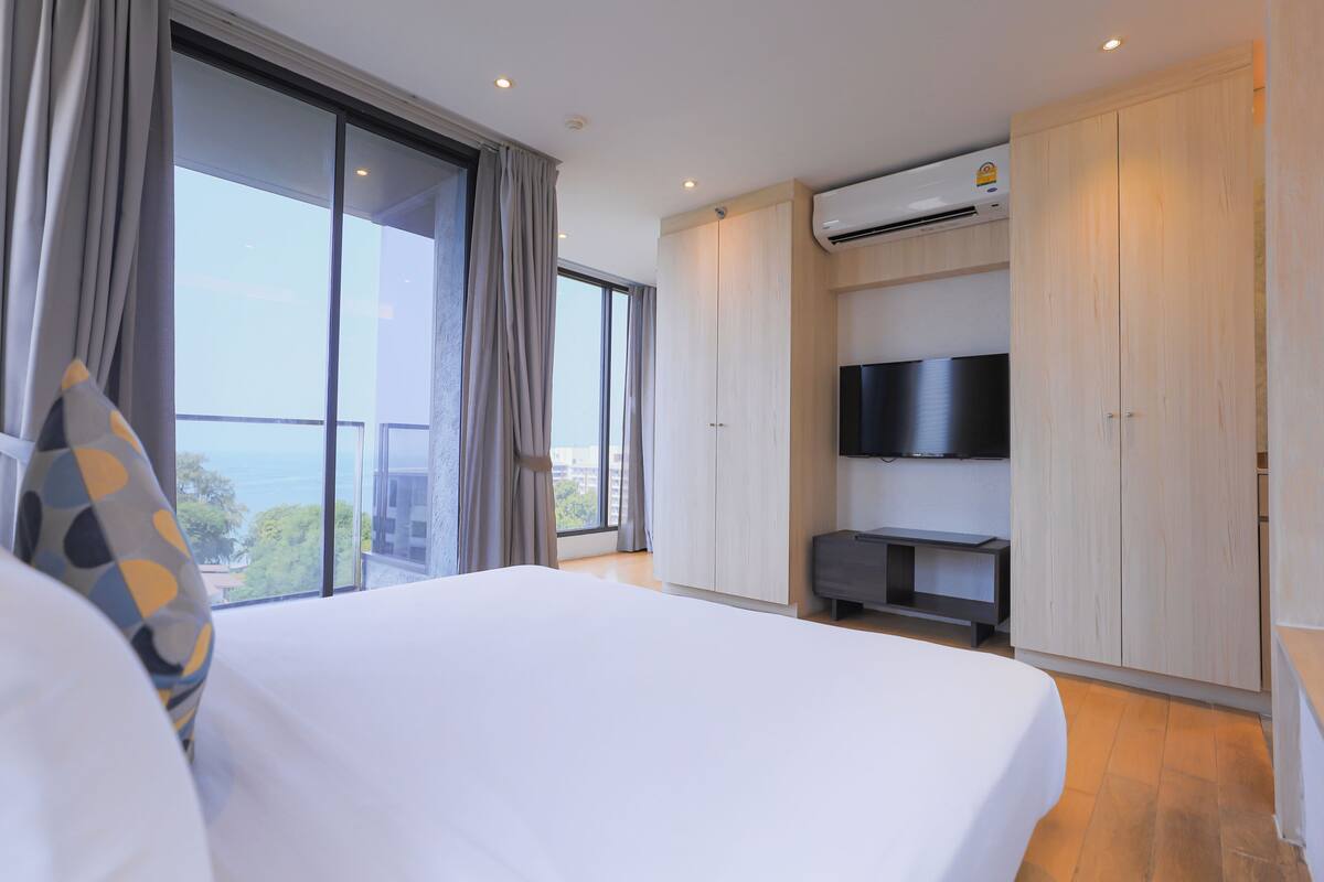 Habitación de hotel con una cama grande, televisión, armario y balcón con vistas.