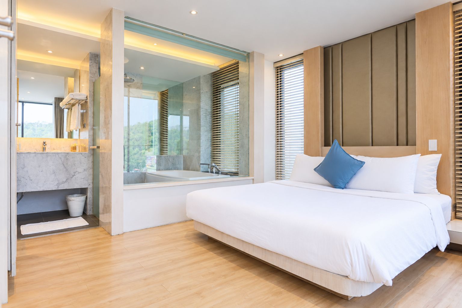 Ein modernes Schlafzimmer mit einem großen Bett, einem eingebauten Fenster und einem Badezimmer mit Marmorwaschtisch.