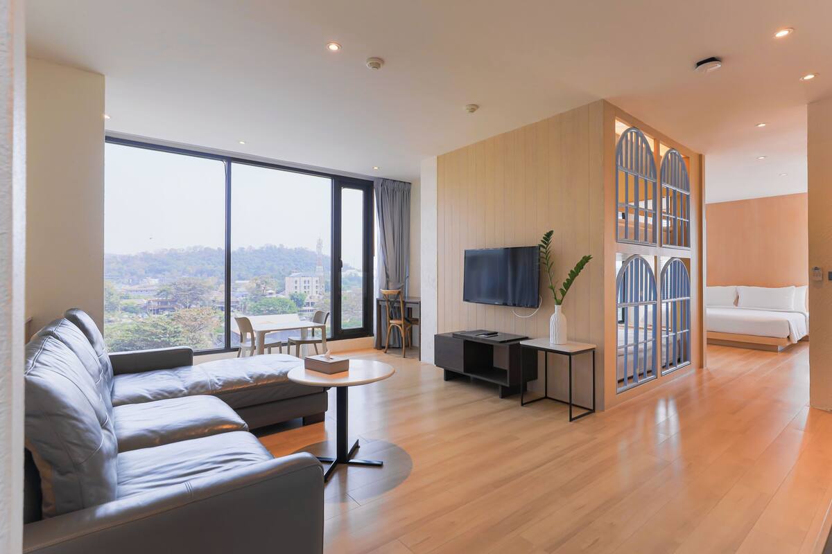Una sala de estar moderna con un sofá, una mesa de centro, un televisor y un ventanal con vistas a la ciudad.