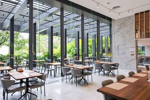 Una sala da pranzo moderna e interna con pareti in vetro, diversi tavoli e sedie.
