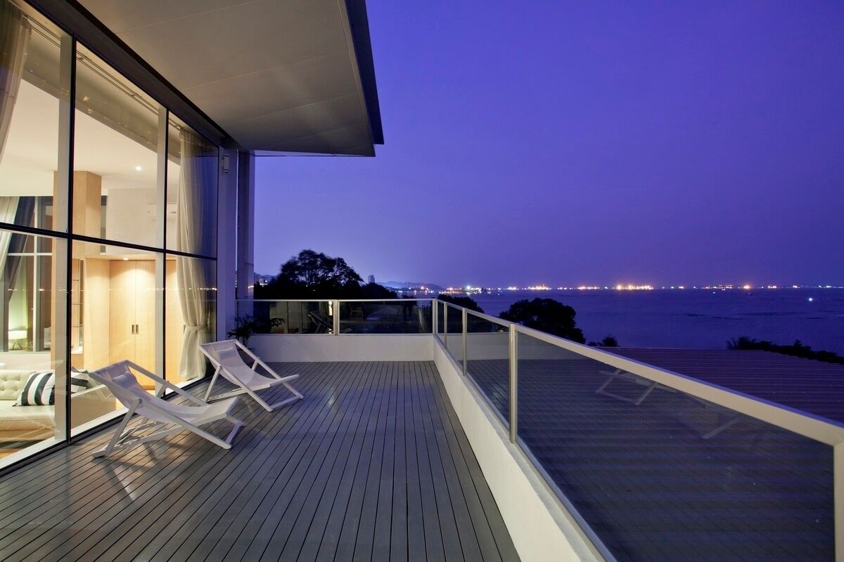Une maison moderne dotée d’un balcon donnant sur une étendue d’eau, au crépuscule.