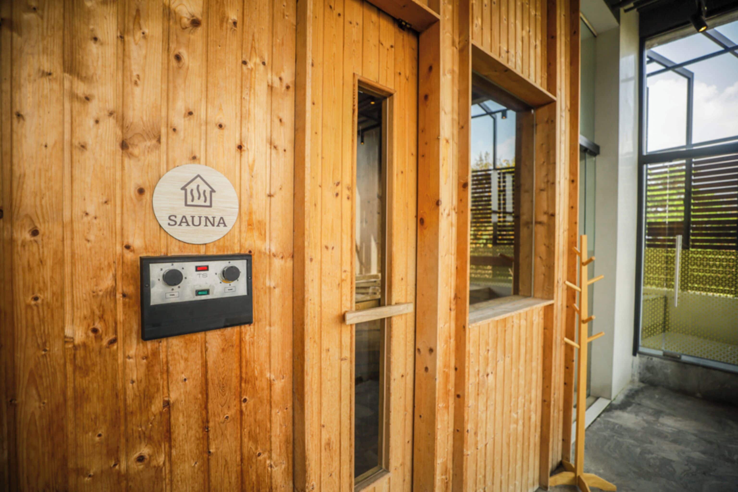 Un sauna en bois, avec une pancarte indiquant sa fonction, un panneau de commande et une fenêtre.