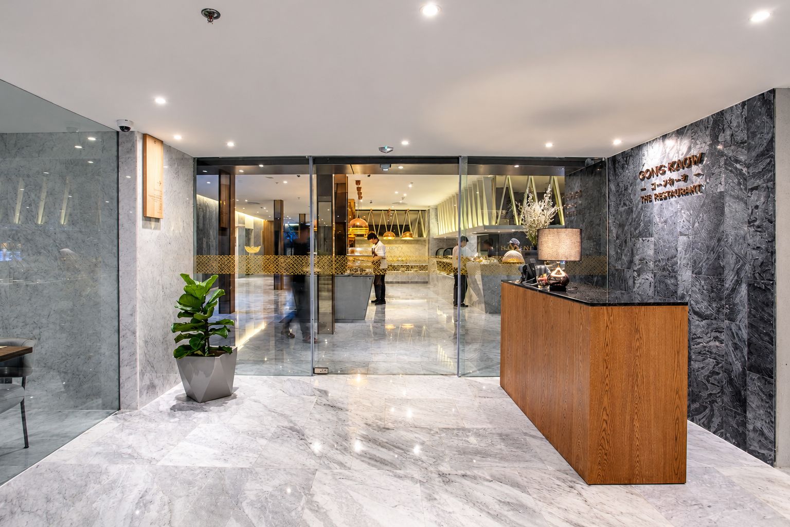 A hotel reception area with a marble floor, a reception desk, and a glass partition.