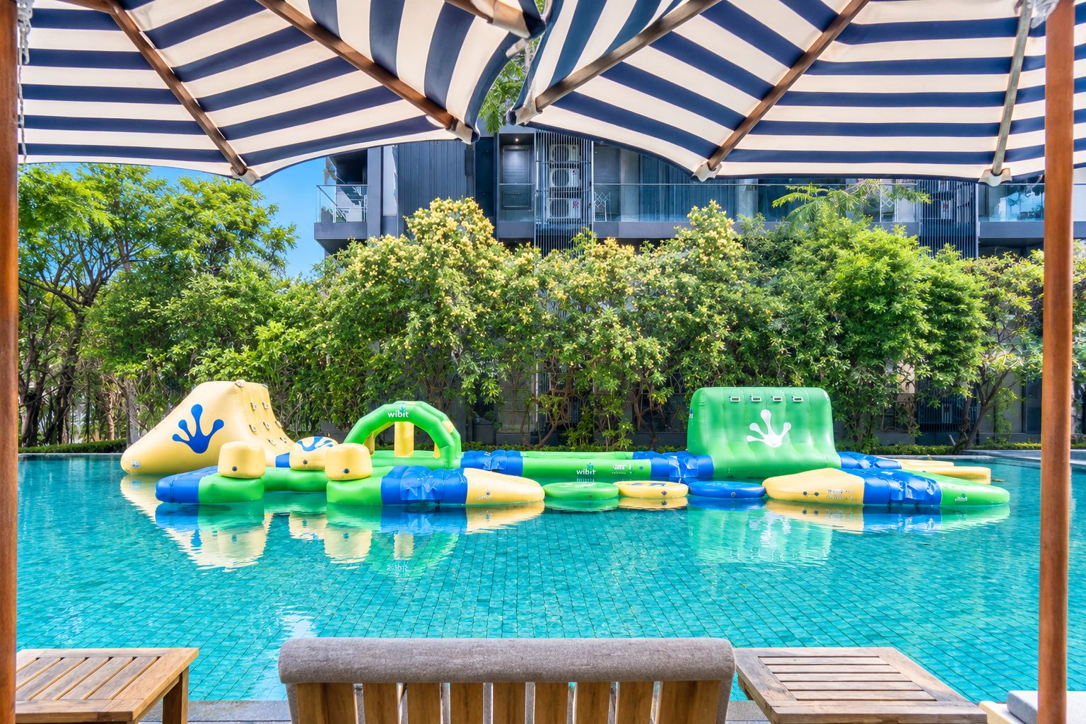 A swimming pool with inflatable water toys and a wooden deck with chairs.
