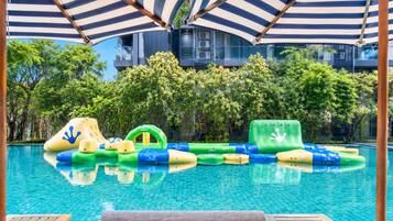 A swimming pool with inflatable water toys and a wooden deck with chairs.