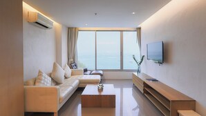 A modern living room with a sofa, a coffee table, a TV, and a large window with a view.