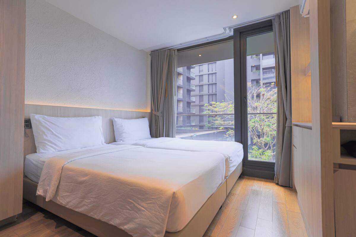 Habitación de hotel con una cama grande, una ventana con cortinas y vistas a un edificio.