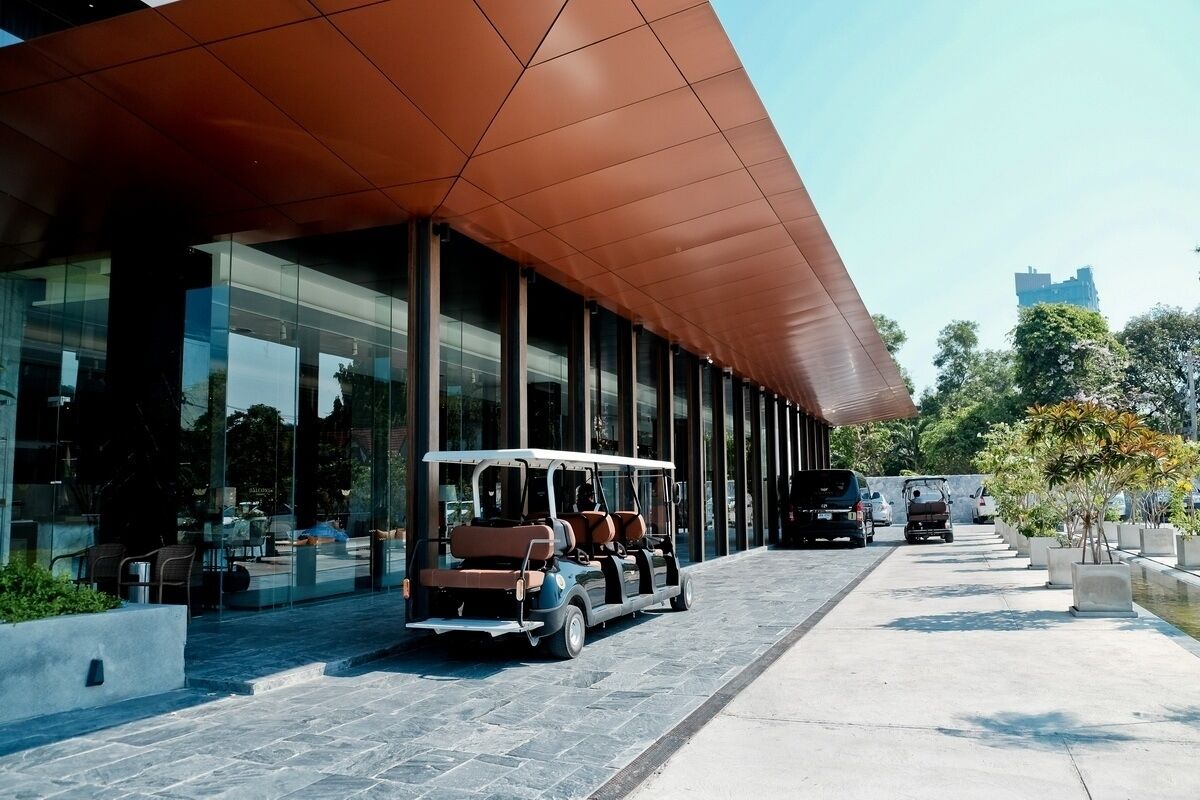 A modern building with a covered walkway, glass windows, and outdoor seating.