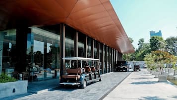A modern building with a covered walkway, glass windows, and outdoor seating.