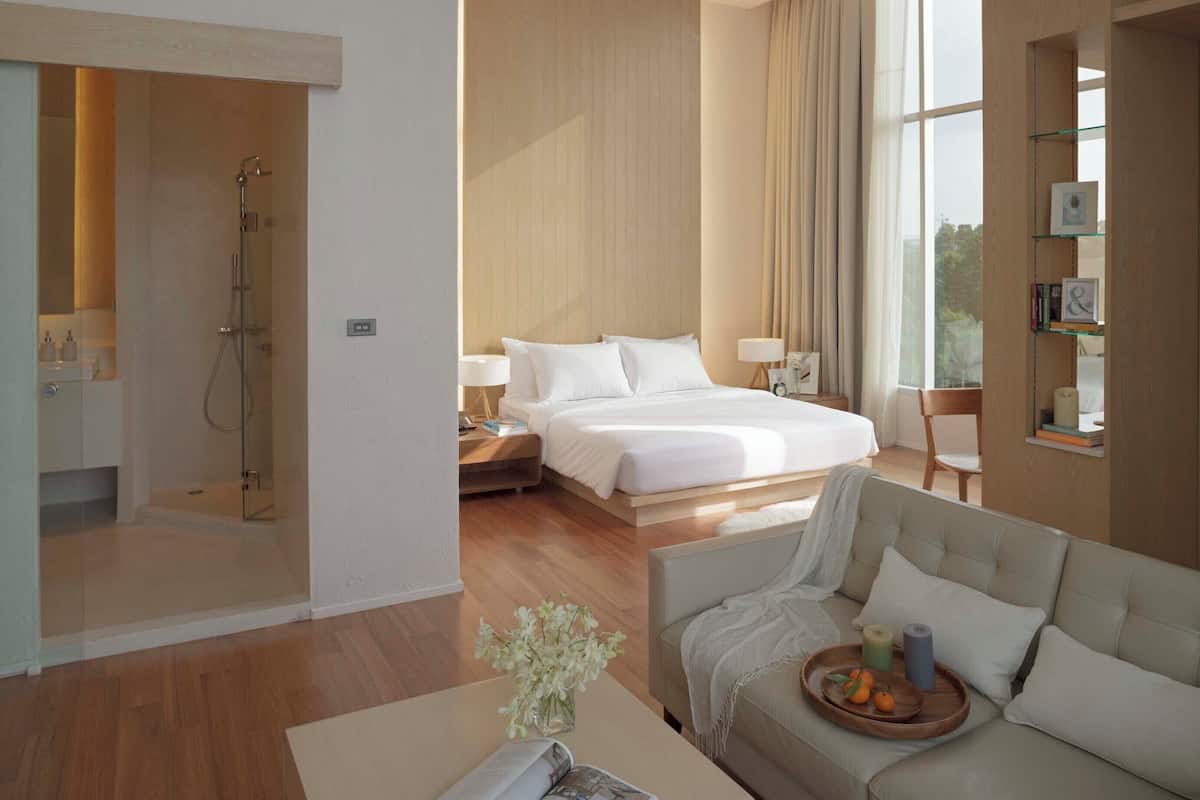 Una habitación de hotel moderna con un dormitorio independiente, zona de estar y baño.