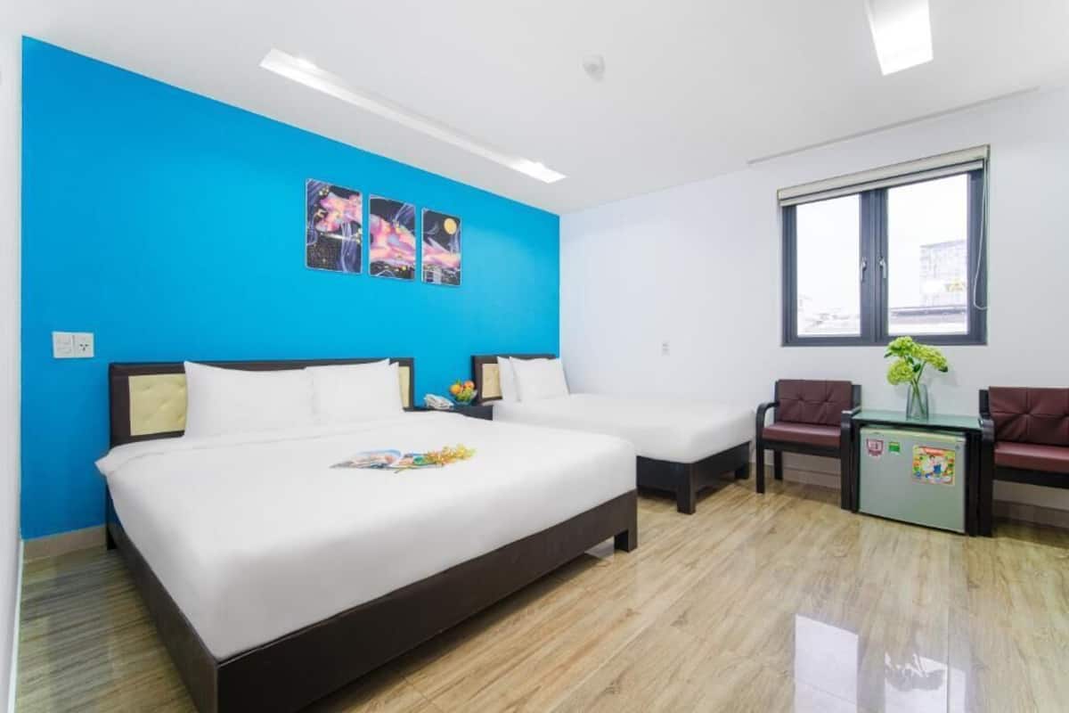 A hotel room with a large bed, a smaller bed, a desk with a chair, and a window.
