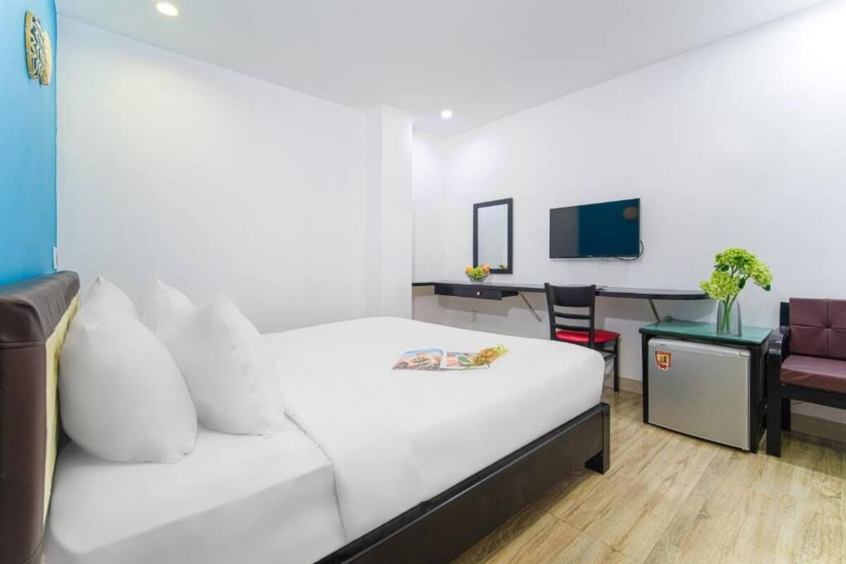 A hotel room with a bed, a desk, a chair, a TV, and a small fridge.