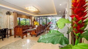 A spacious hotel lobby with a wooden reception desk, comfortable seating, and large windows offering a view of the outdoors. - La Maison Da Nang Beach (Da Nang)