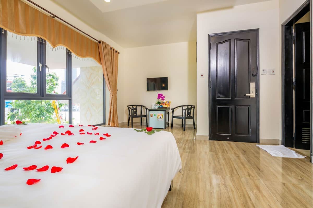 A hotel room with a bed, a desk, a TV, and a door.
