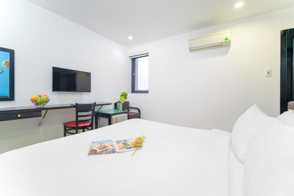 A hotel room with a bed, a desk, a chair, a television, and an air conditioning unit.