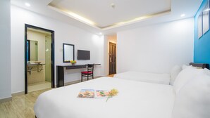 A hotel room with a large bed, a desk with a chair, a television, and a bathroom visible through an open door. - La Maison Da Nang Beach (Da Nang)
