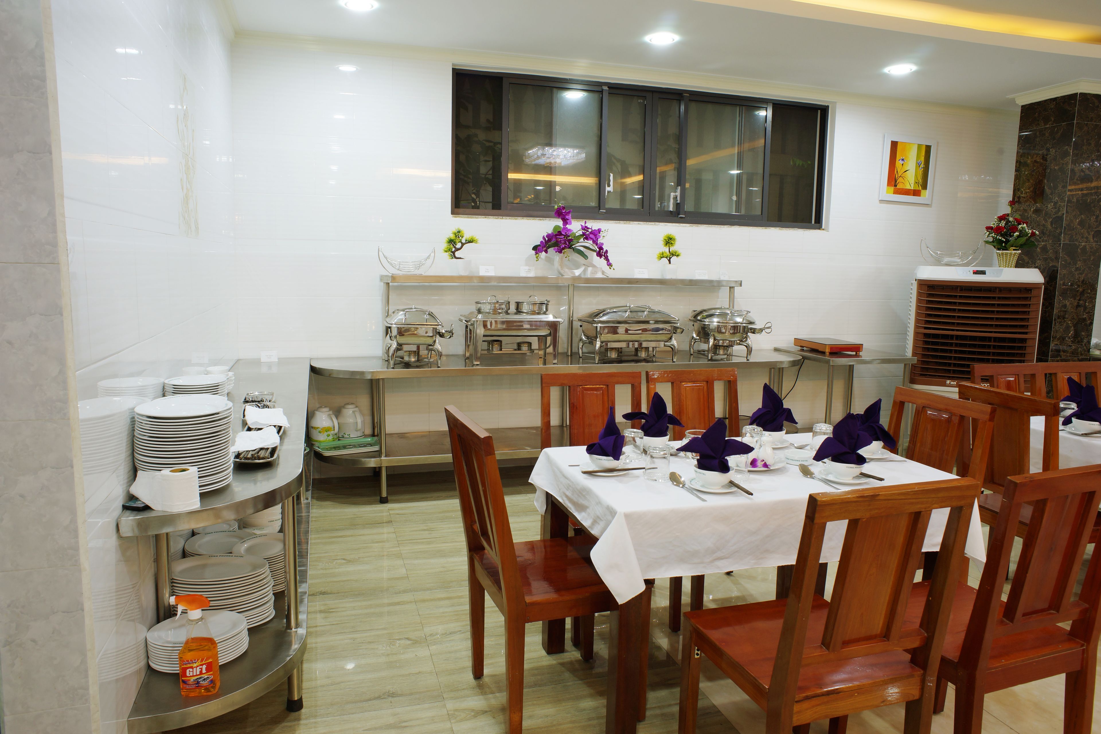 Comedor con barra libre, sillas de madera y mantel blanco.