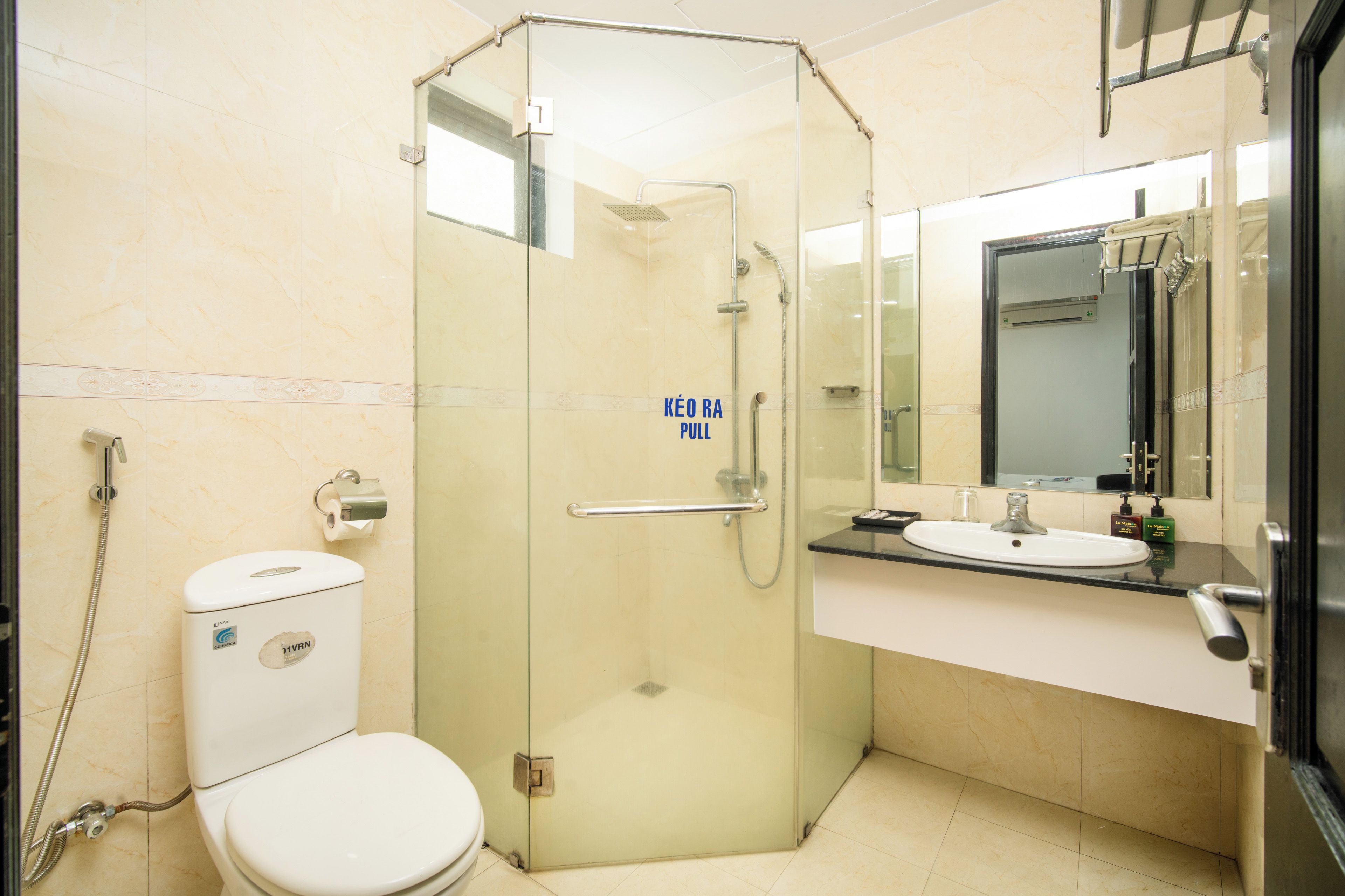 A modern bathroom with a glass-enclosed shower, a toilet, and a sink with a mirror above it.