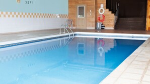 A swimming pool with a checkered tile border, a metal ladder, and a wooden door in the background. - Brackley Beach Northwinds Inn and Suites (Brackley Beach)