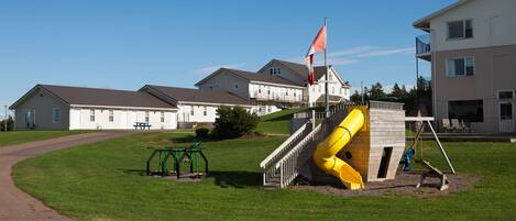 A playground with a yellow slide, a flag, and a walking path.