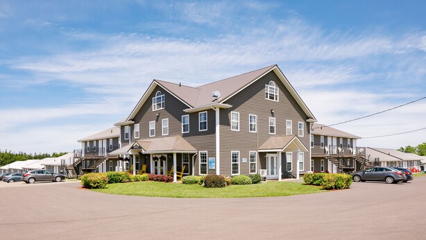 A multi-story hotel with a central entrance, multiple balconies, and a parking area. - Brackley Beach Northwinds Inn and Suites (Brackley Beach)