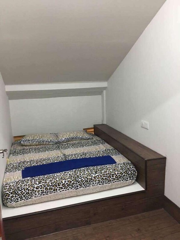 A small, narrow room with a bed featuring a leopard print cover and a blue accent.