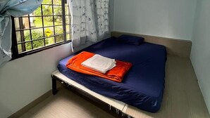 A small, single-bed room with a ceiling fan, a window with curtains, and a view of greenery outside. - Step Inn Guest House (Kuala Lumpur)