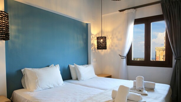 A hotel room with two beds, white bedding, and towels on the beds. - Mika Villas & Suites (Hersonissos)
