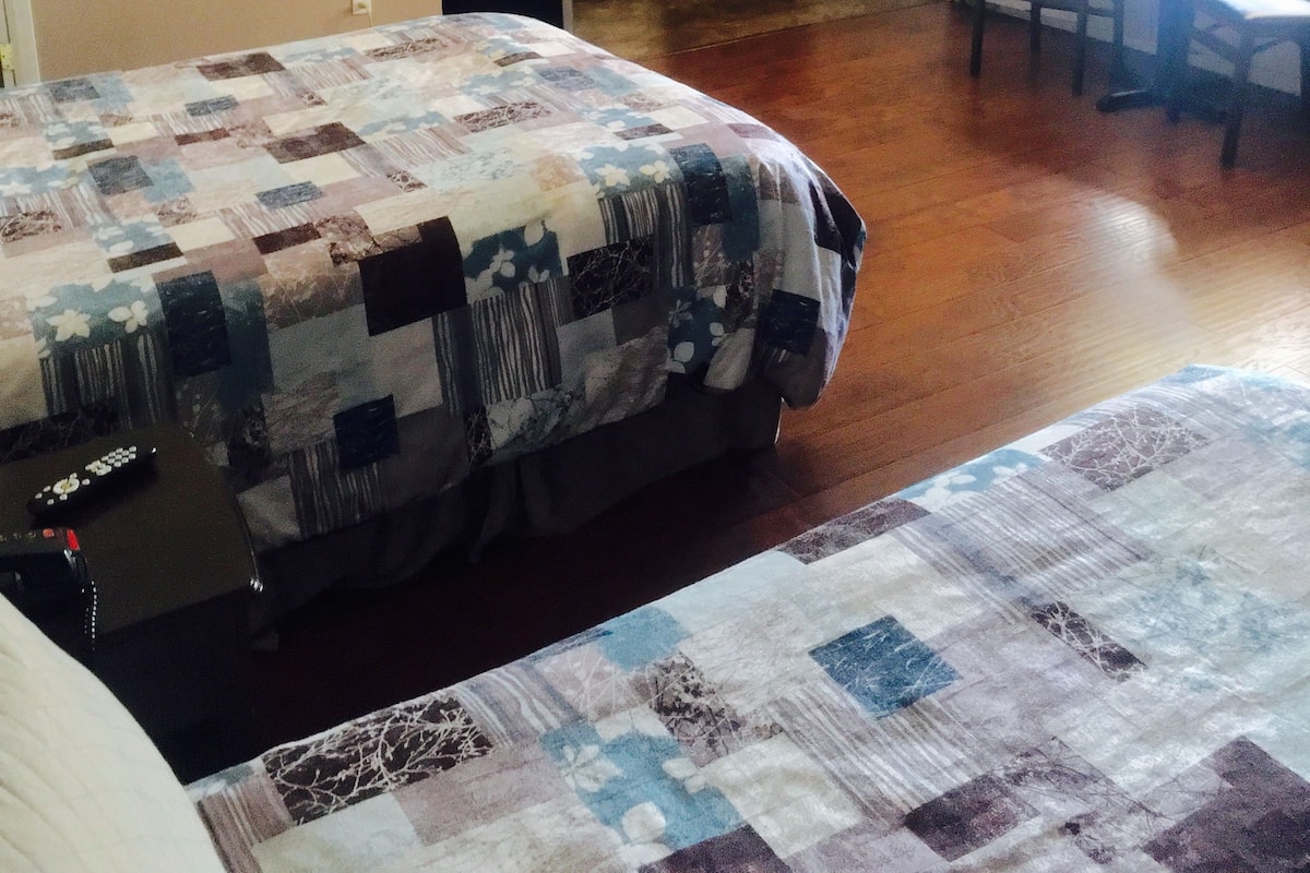 A room with a bed, a desk, and a kitchenette.