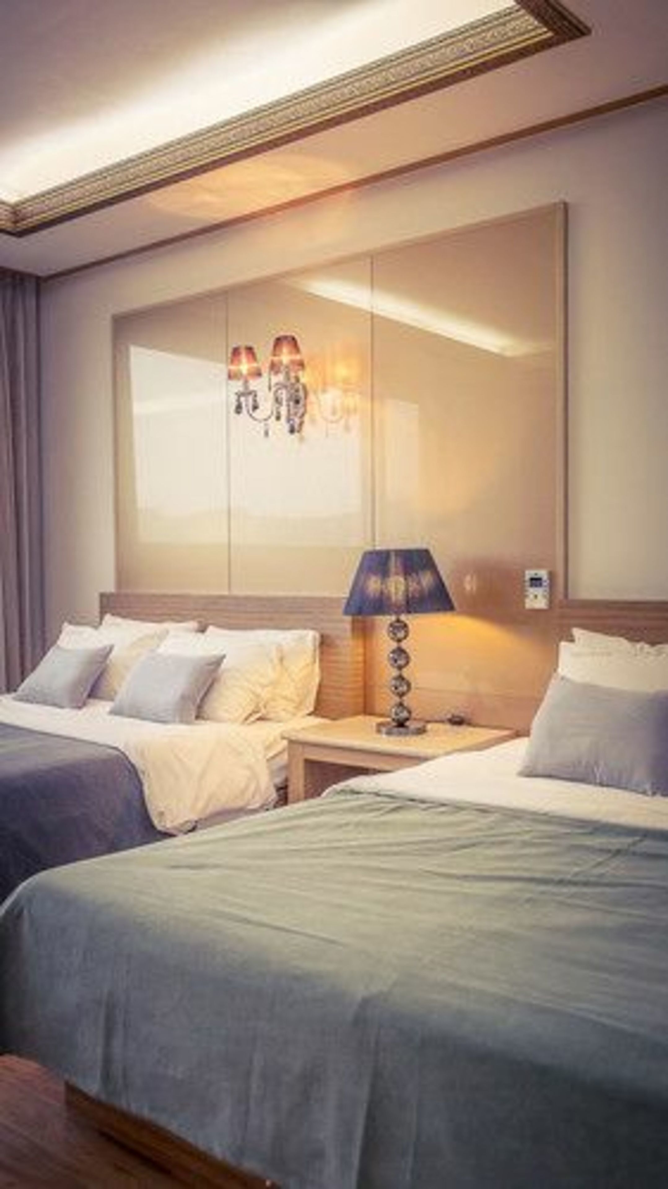 A hotel room with two beds, a nightstand, a lamp, and a wall-mounted mirror.