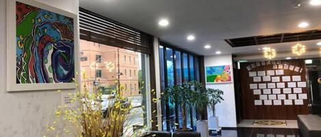 A modern lobby with a reception desk, seating area, and artwork on the walls.