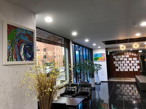 Un vestíbulo moderno con mostrador de recepción, zona de estar y obras de arte en las paredes.
