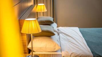 Una cama bien hecha con cabecera, lámpara de noche y almohada.